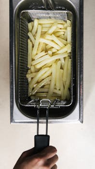 Close-Up Shot of a Person Frying French Fries